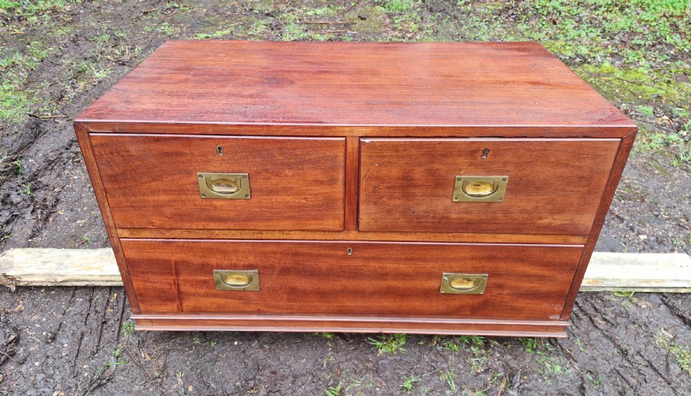 A low mahogany campaign chest of drawers with recessed brass handles and keyholes.