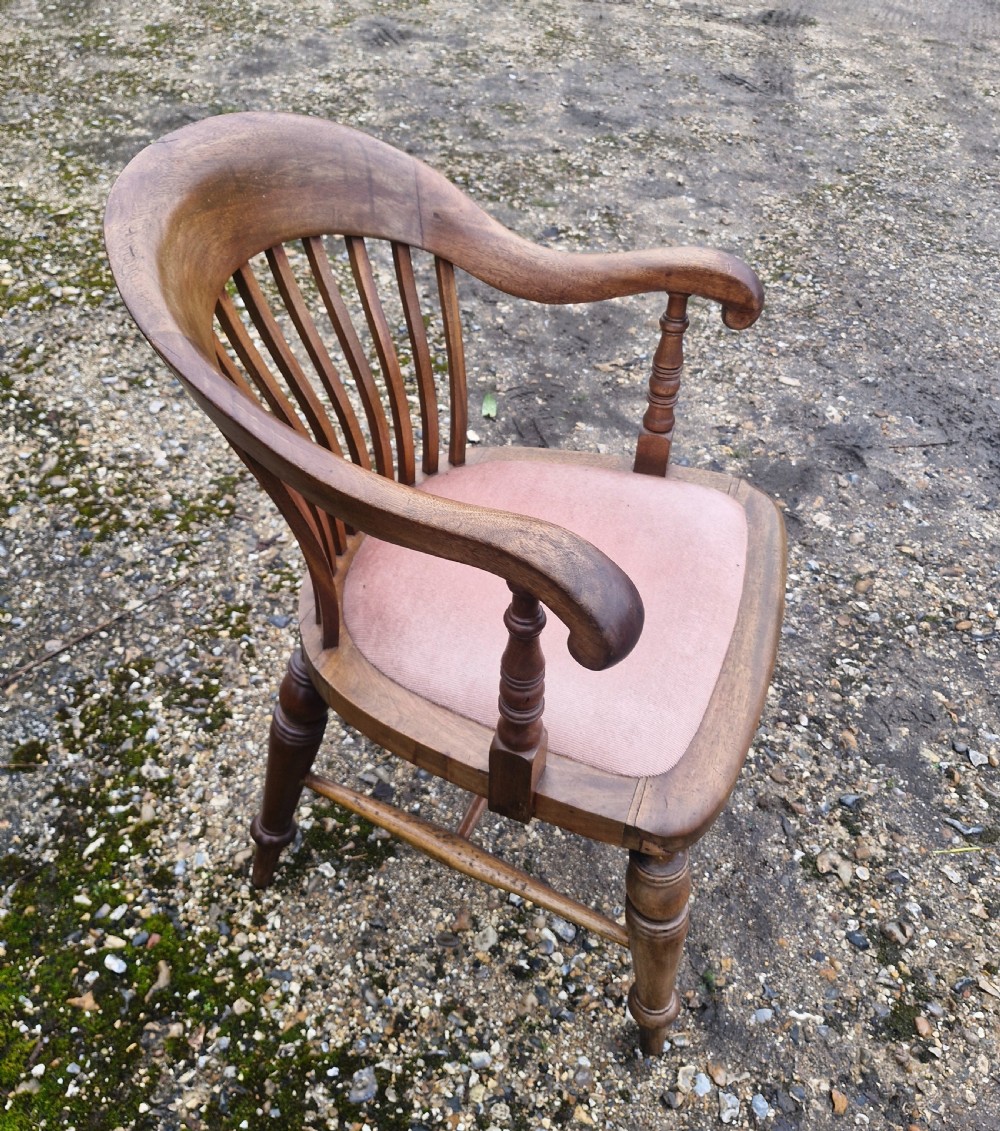 An early 20th-century mahogany military desk armchair featuring a spindle back, turned front legs, and a padded seat. View X