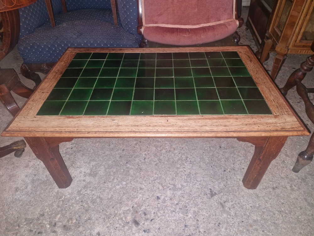 A low rectangular oak coffee table featuring an inset top crafted from square dark green glazed ceramic tiles.