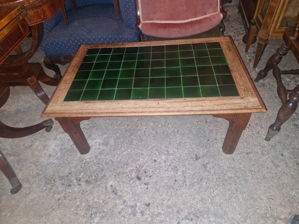 A low rectangular oak coffee table featuring an inset top crafted from square dark green glazed ceramic tiles. View V
