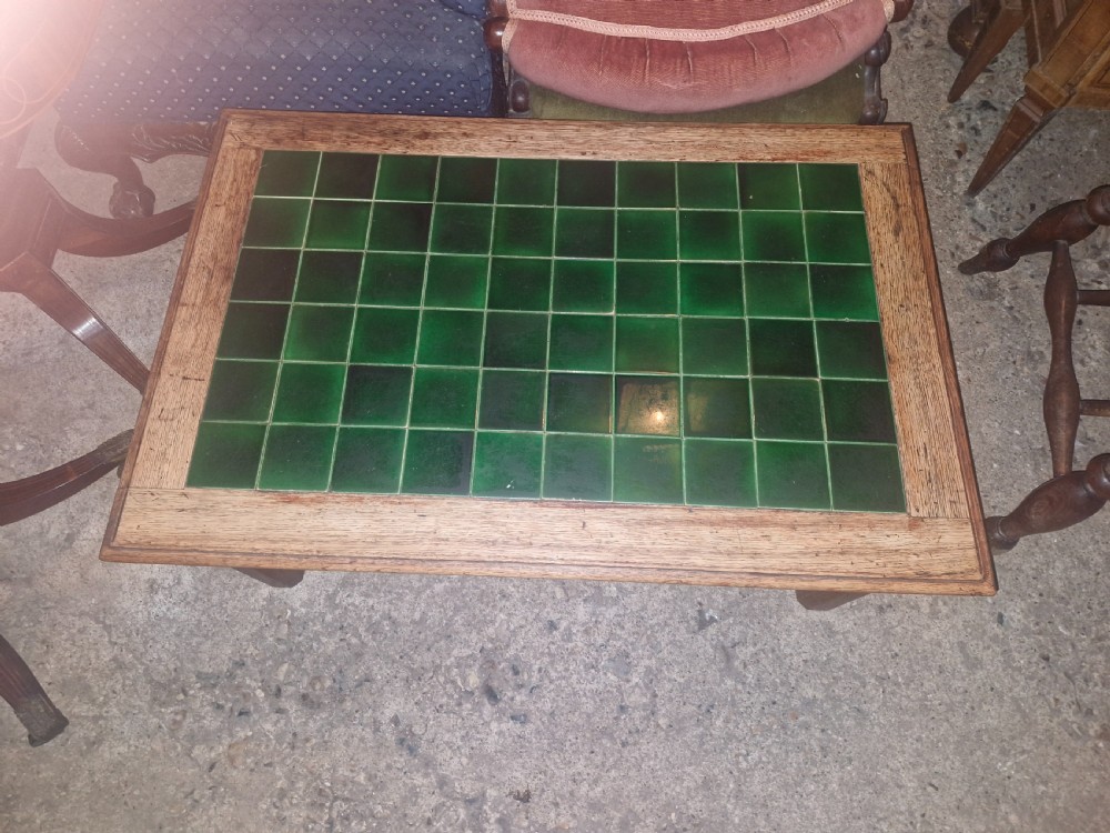 A low rectangular oak coffee table featuring an inset top crafted from square dark green glazed ceramic tiles. View VI