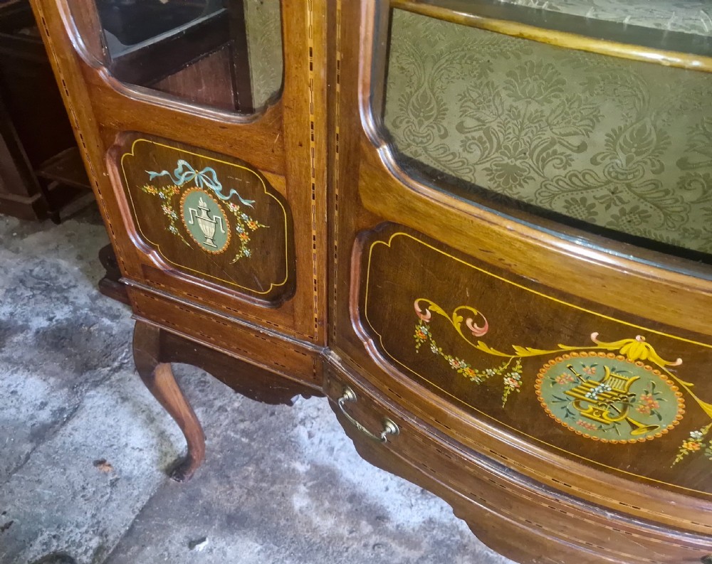 An Edwardian mahogany display cabinet with three glazed doors, hand-painted classical urn motifs, satinwood inlay, and cabriole legs. View III