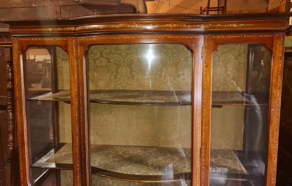 An Edwardian mahogany display cabinet with three glazed doors, hand-painted classical urn motifs, satinwood inlay, and cabriole legs. View VIII