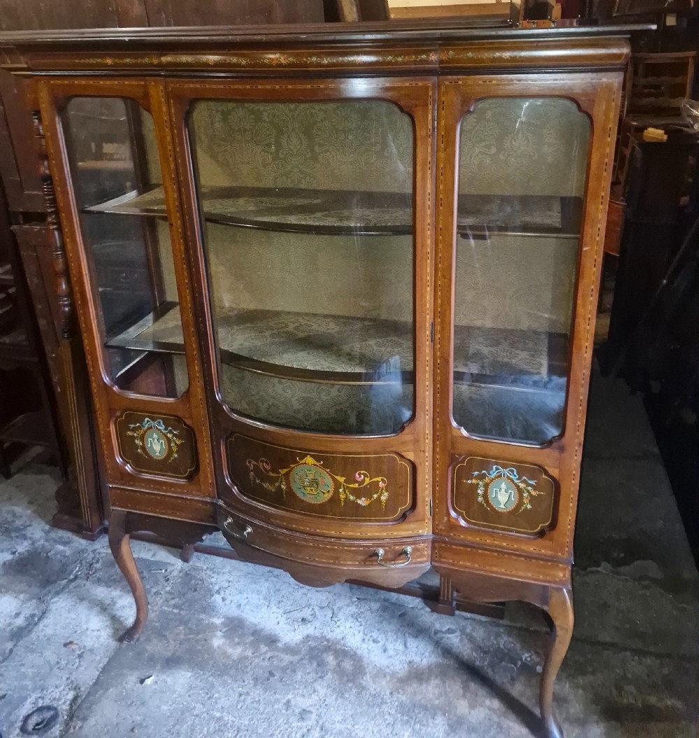 An Edwardian mahogany display cabinet with three glazed doors, hand-painted classical urn motifs, satinwood inlay, and cabriole legs. View IX