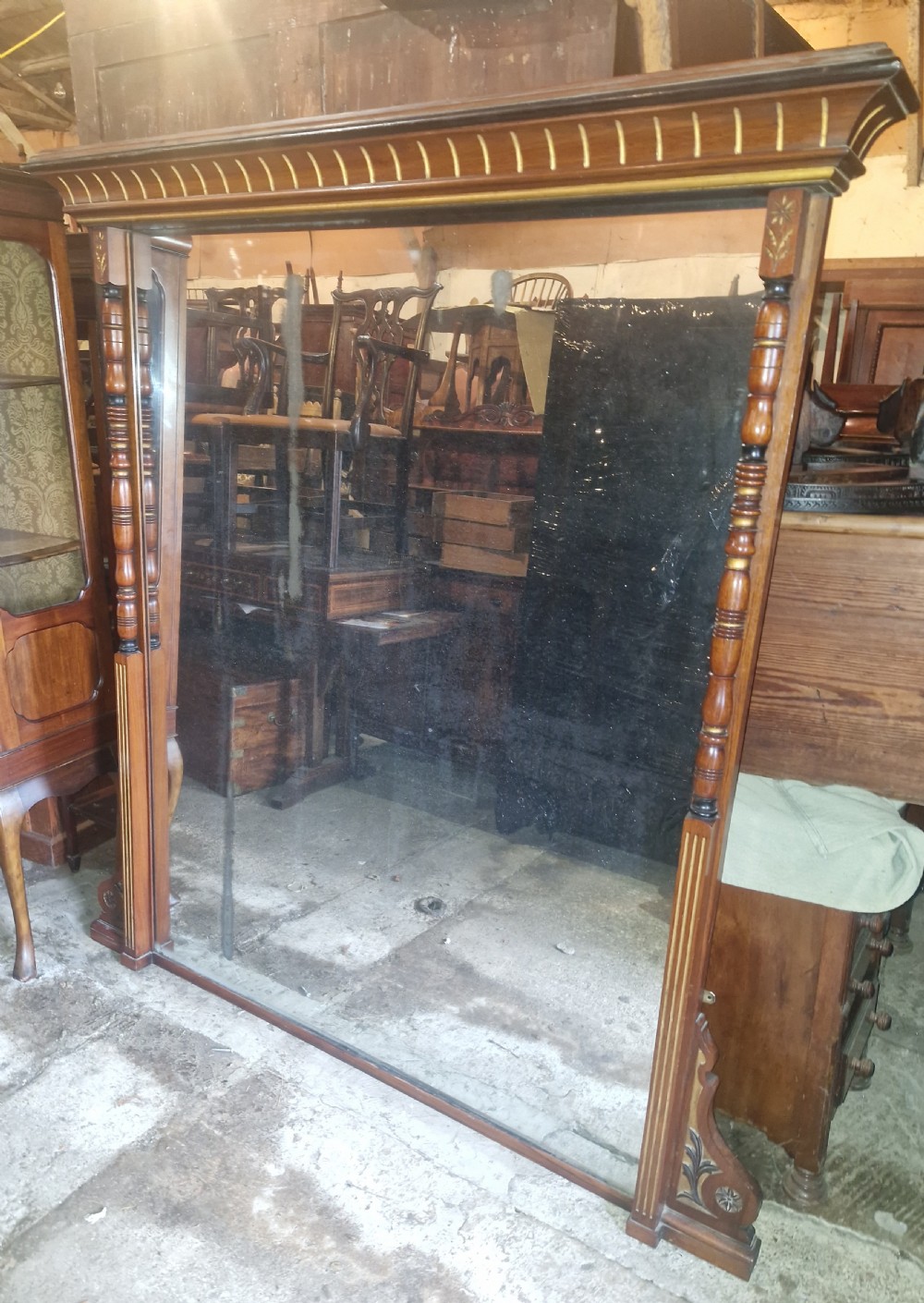 A large Victorian walnut hall mirror featuring a projected upper cornice, turned side columns with gilt highlights, and inlaid corner details.