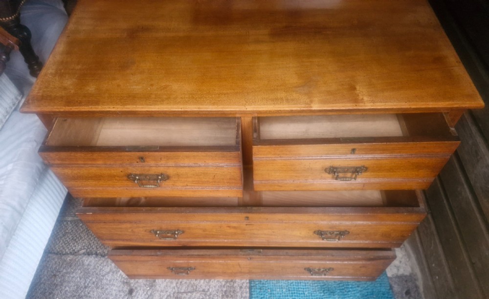 A late Victorian warm brown walnut chest of drawers featuring two short drawers over two long drawers with brass drop handles and a low top gallery. View II