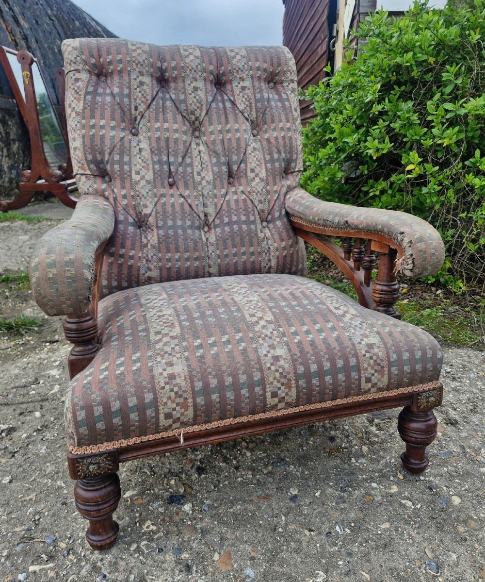 A late Victorian armchair featuring deep button-tufted fabric upholstery, turned front legs, and padded armrests supported by small turned wooden spindles. View II
