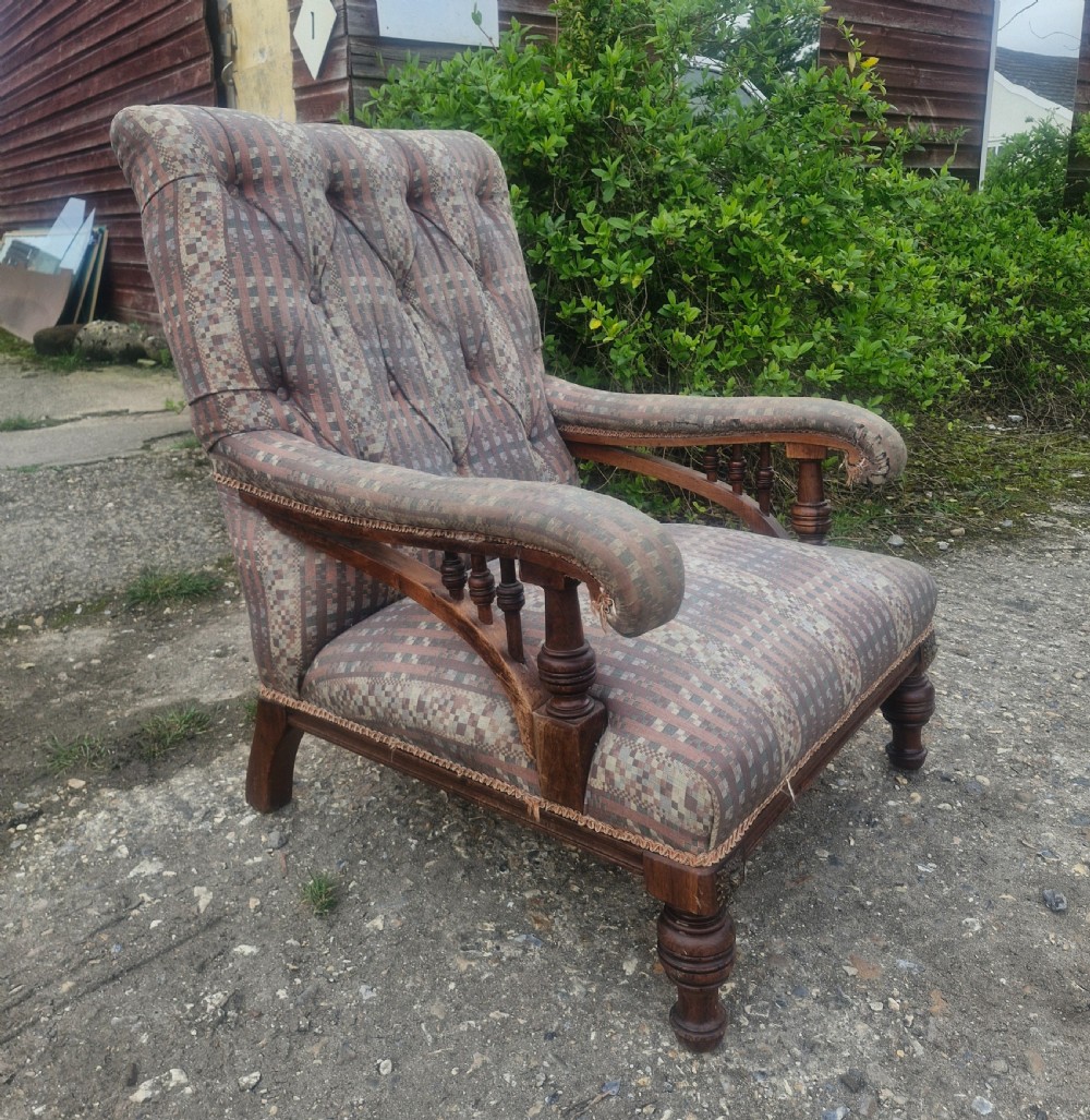 A late Victorian armchair featuring deep button-tufted fabric upholstery, turned front legs, and padded armrests supported by small turned wooden spindles. View III