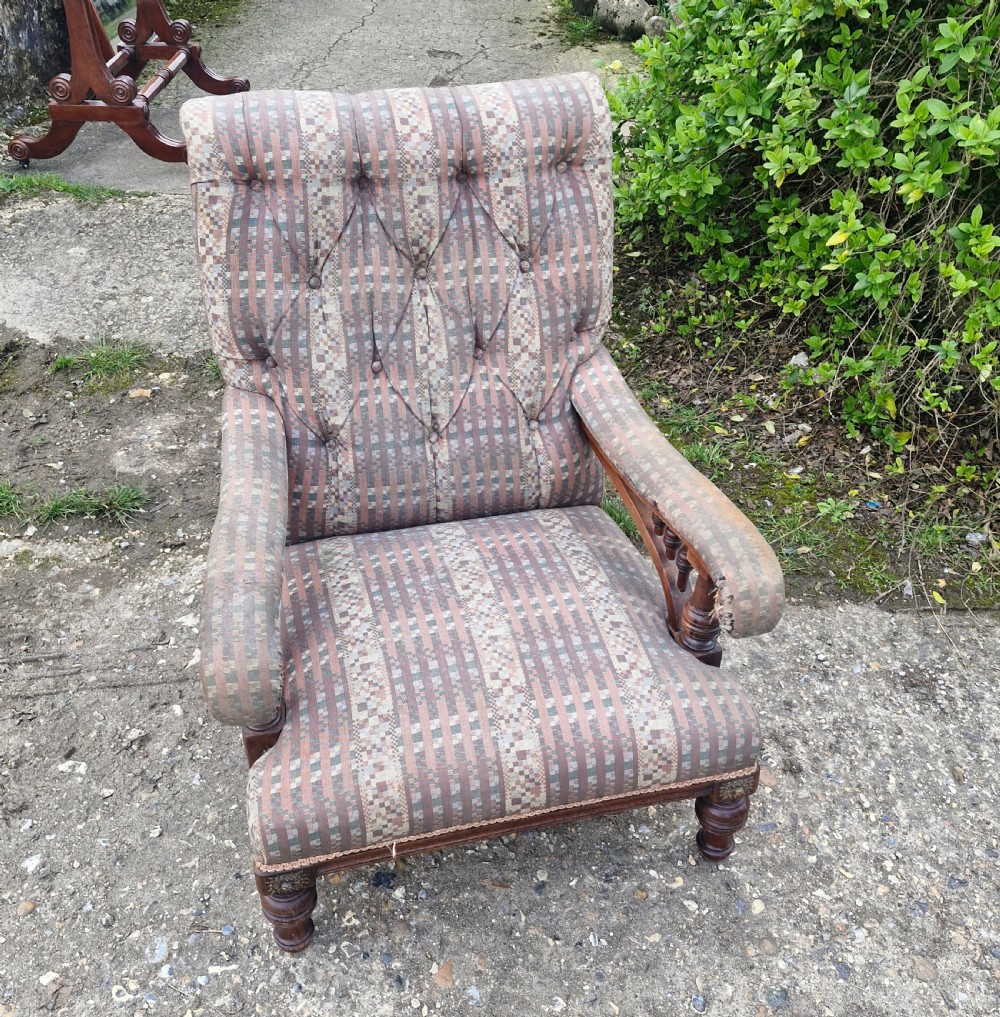 A late Victorian armchair featuring deep button-tufted fabric upholstery, turned front legs, and padded armrests supported by small turned wooden spindles. View V