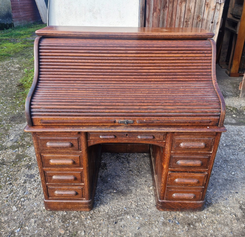 A traditional solid oak pedestal desk with a curved roll top tambour front and multiple side drawers. View II