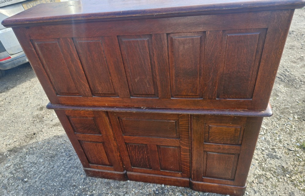 A traditional solid oak pedestal desk with a curved roll top tambour front and multiple side drawers. View X