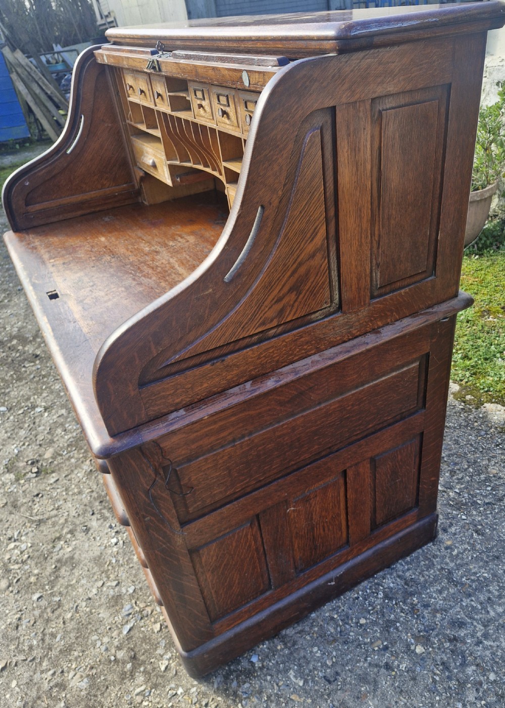 A traditional solid oak pedestal desk with a curved roll top tambour front and multiple side drawers. View XII