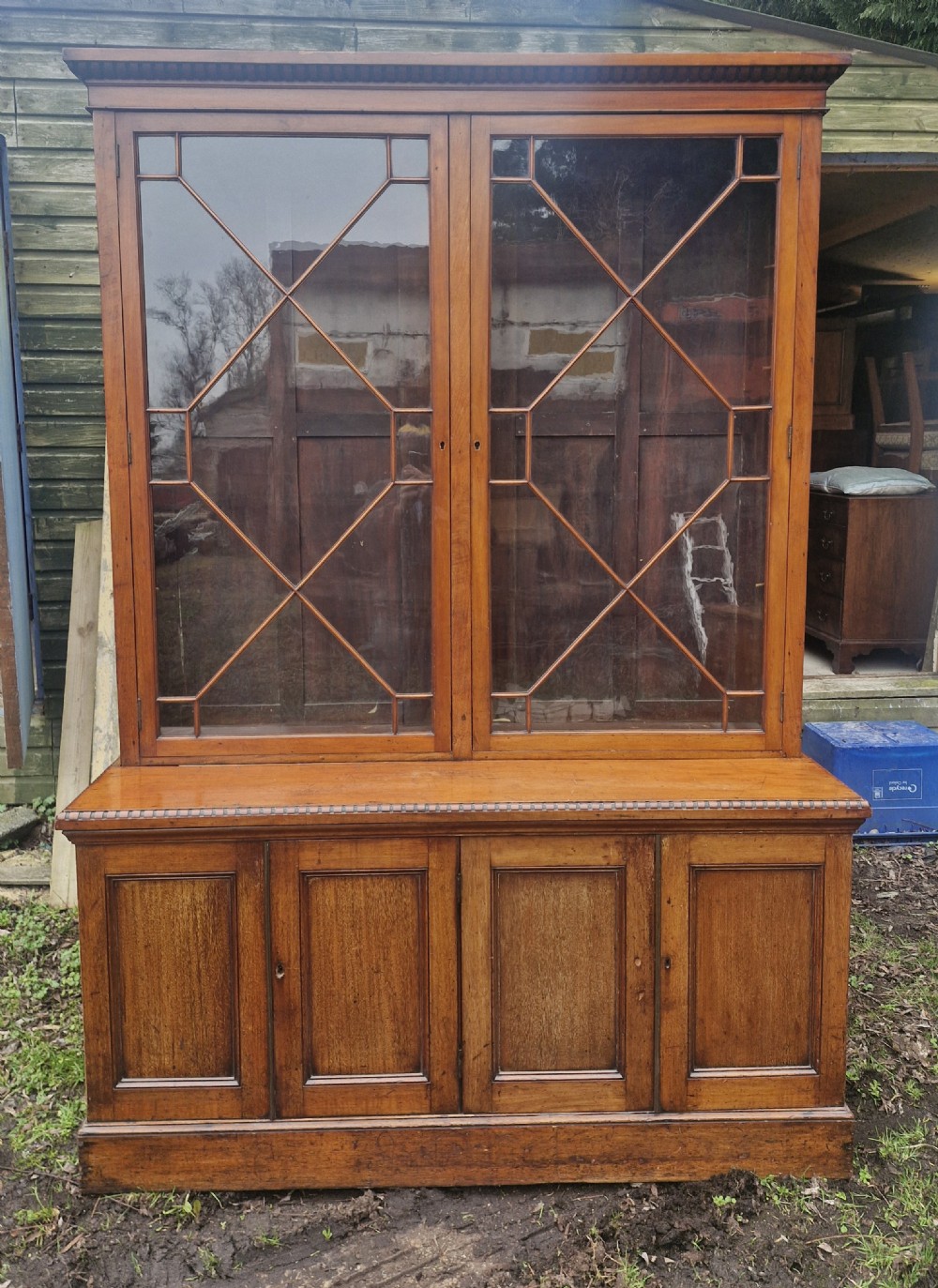 A two-part Victorian glazed wooden bookcase cabinet featuring upper astragal glass doors and four lower solid timber panelled cupboard doors.