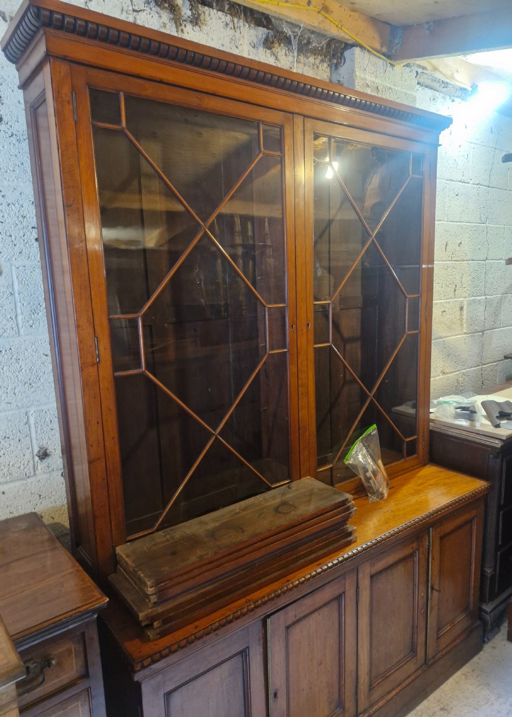 A two-part Victorian glazed wooden bookcase cabinet featuring upper astragal glass doors and four lower solid timber panelled cupboard doors. View VI
