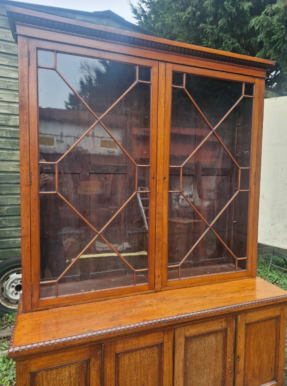A two-part Victorian glazed wooden bookcase cabinet featuring upper astragal glass doors and four lower solid timber panelled cupboard doors. View X