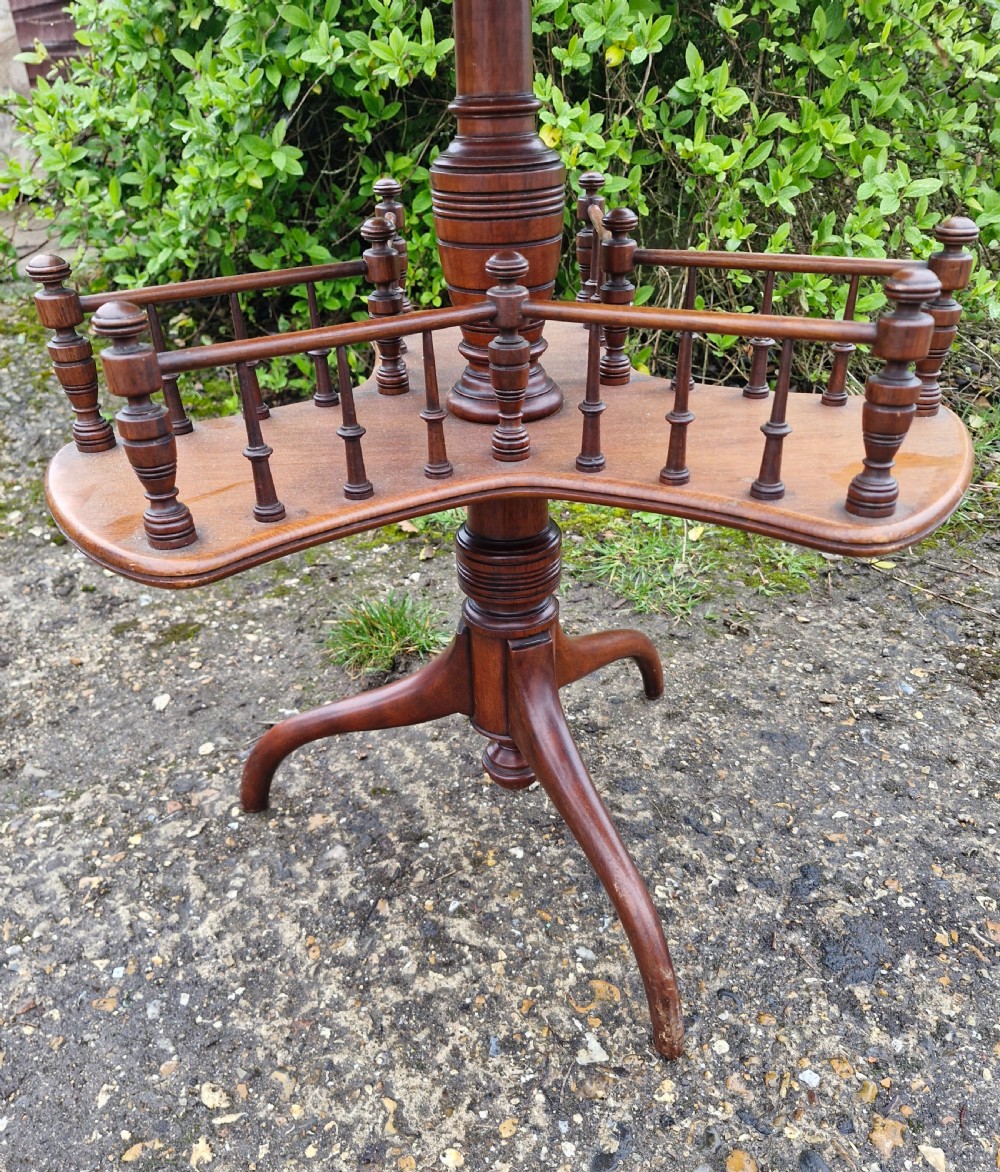 A Victorian mahogany revolving wine table featuring a circular top, a lower tier with spindle galleries, a turned central shaft, and three down-swept tripod legs. View II