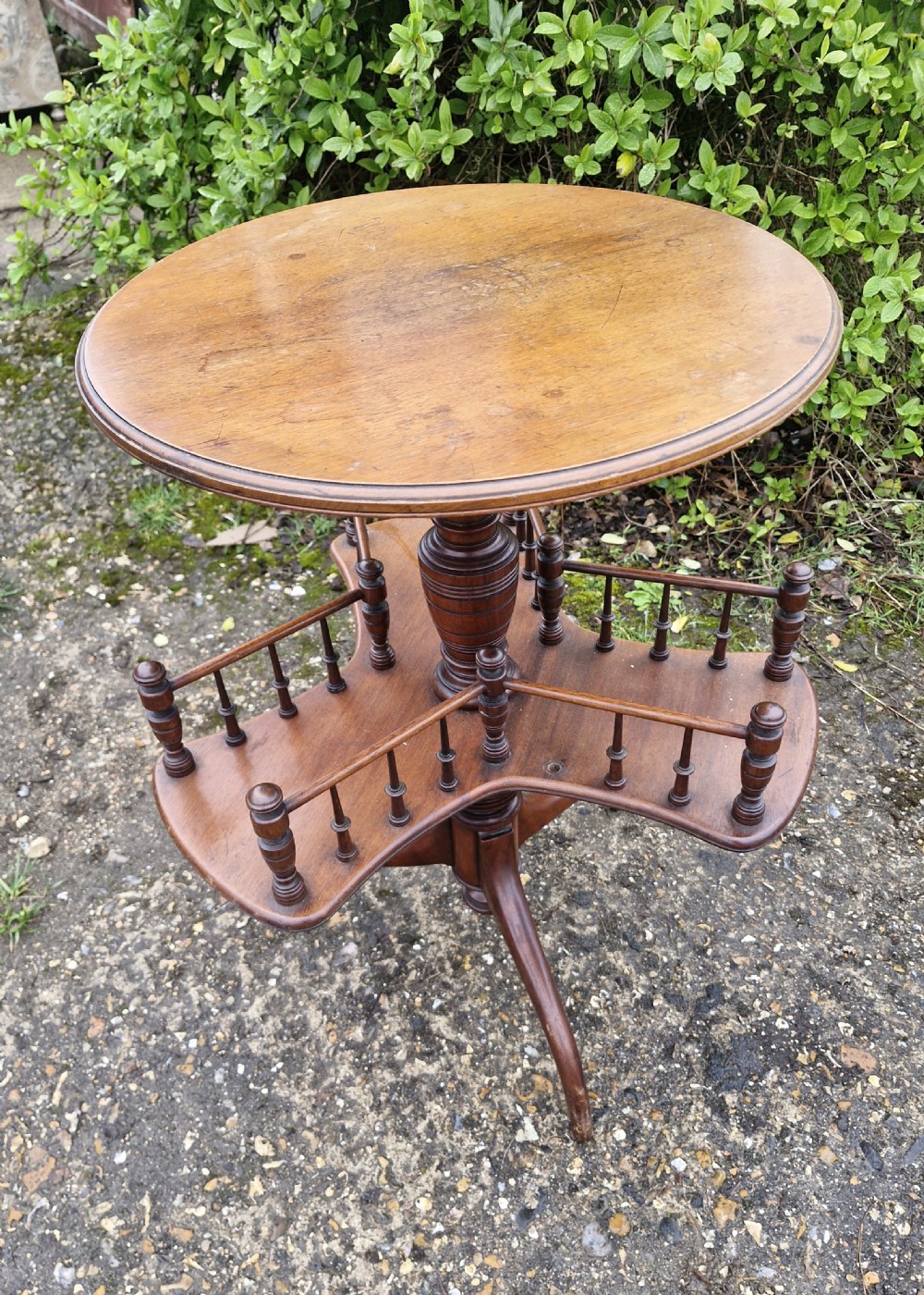 A Victorian mahogany revolving wine table featuring a circular top, a lower tier with spindle galleries, a turned central shaft, and three down-swept tripod legs. View IV