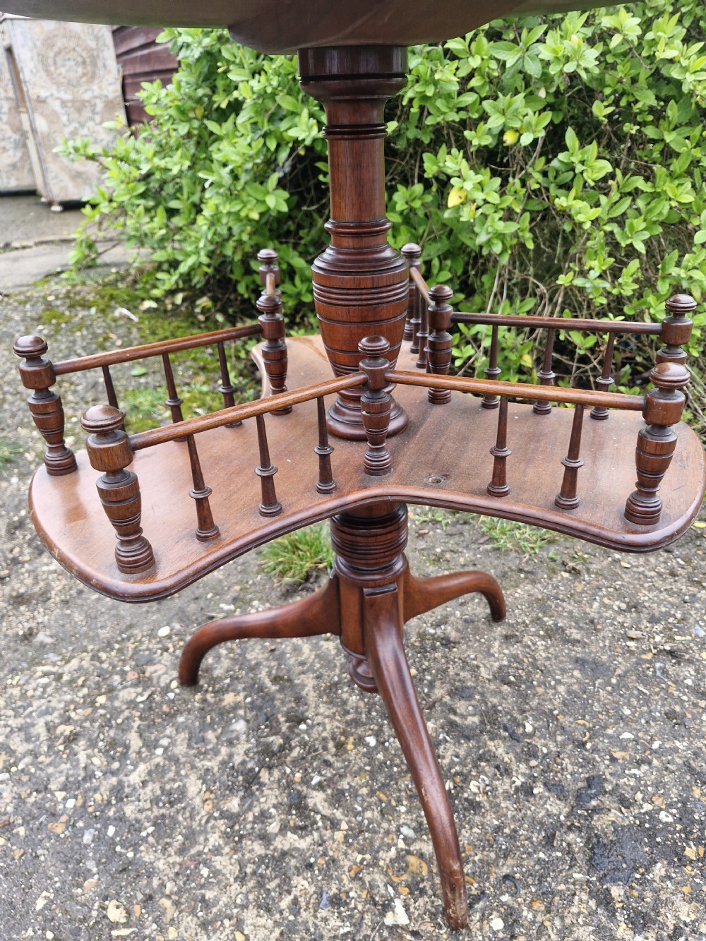 A Victorian mahogany revolving wine table featuring a circular top, a lower tier with spindle galleries, a turned central shaft, and three down-swept tripod legs. View V