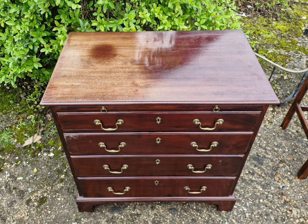 An 18th-century Georgian mahogany chest of drawers featuring four graduated drawers with brass swan-neck handles, a pull-out brushing slide, and bracket feet. View V