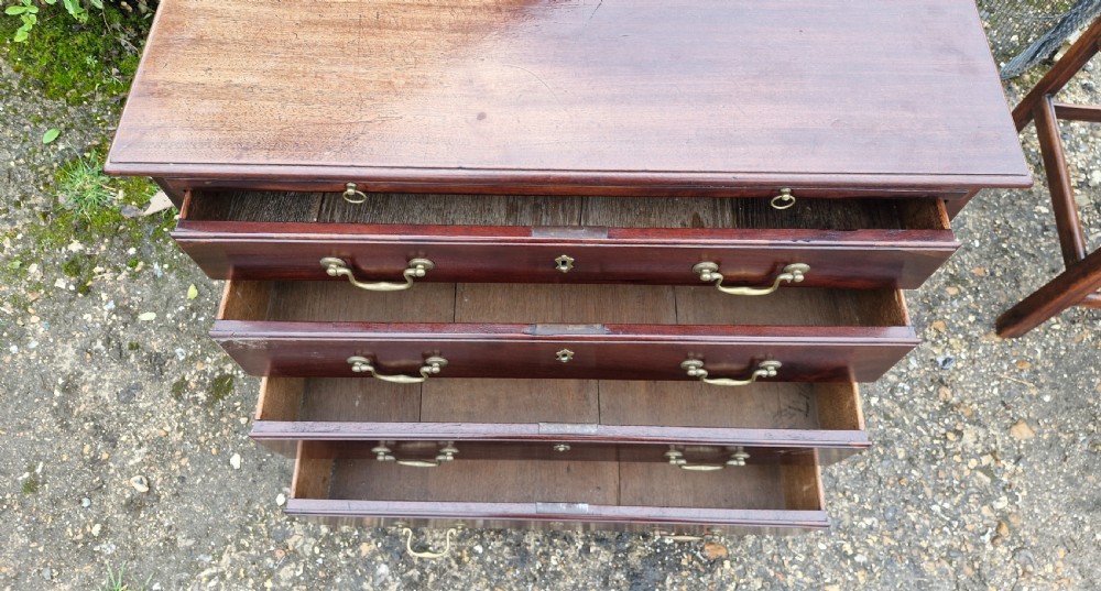 An 18th-century Georgian mahogany chest of drawers featuring four graduated drawers with brass swan-neck handles, a pull-out brushing slide, and bracket feet. View XII