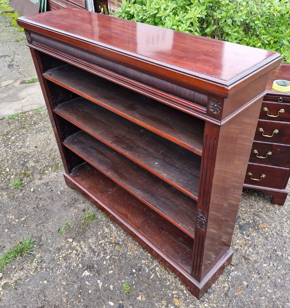 A low late Victorian mahogany open front bookcase featuring four tiers of shelving, reeded pilasters, and carved floral rosettes. View V