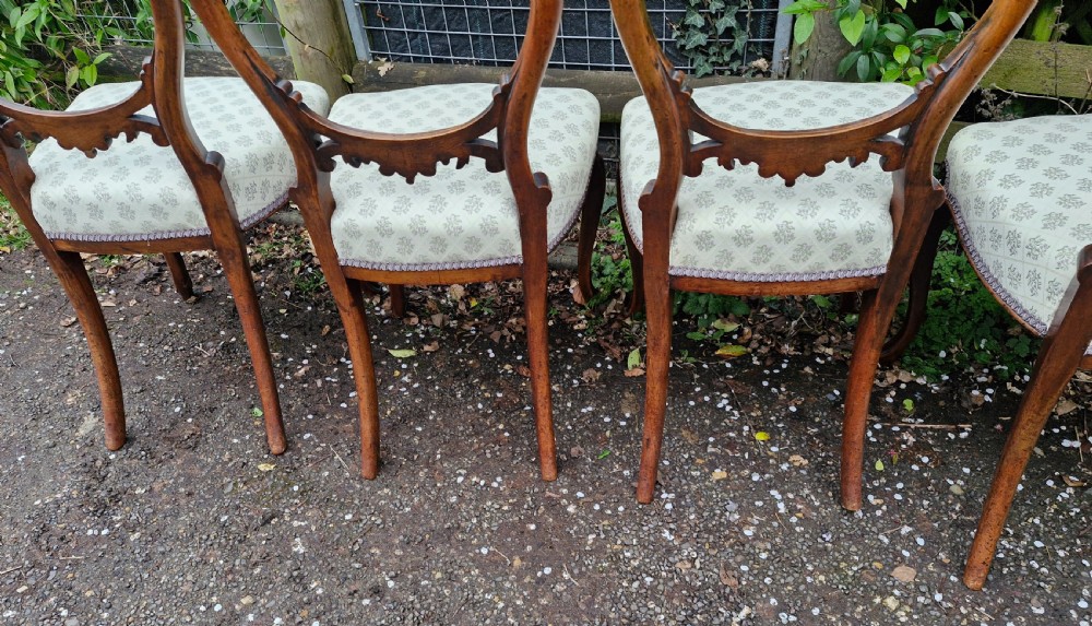 A set of six Victorian walnut balloon back dining chairs featuring carved back splats, cabriole front legs, and pattern-upholstered seats. View III