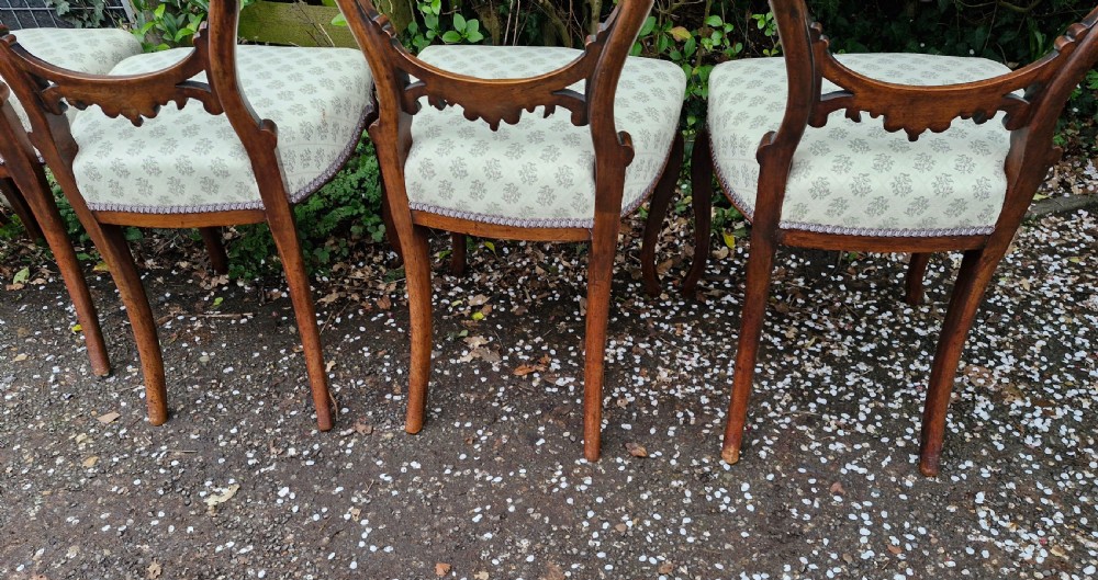 A set of six Victorian walnut balloon back dining chairs featuring carved back splats, cabriole front legs, and pattern-upholstered seats. View IV