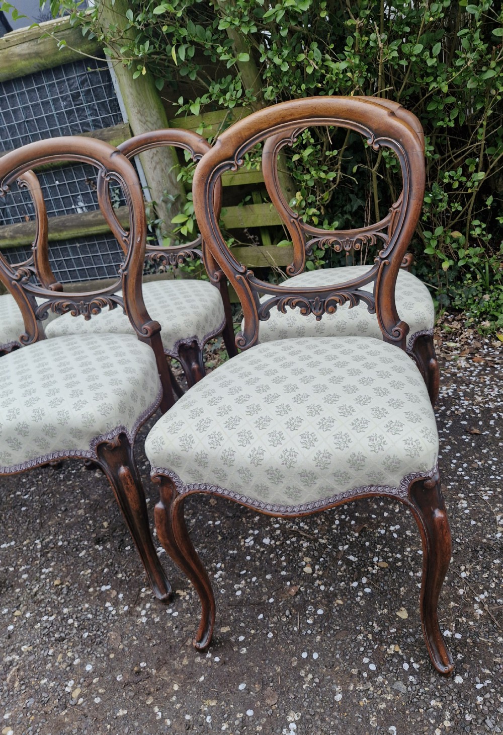 A set of six Victorian walnut balloon back dining chairs featuring carved back splats, cabriole front legs, and pattern-upholstered seats. View VII