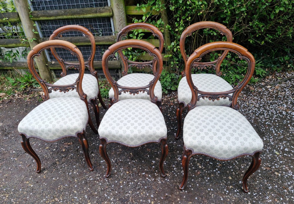 A set of six Victorian walnut balloon back dining chairs featuring carved back splats, cabriole front legs, and pattern-upholstered seats. View VIII