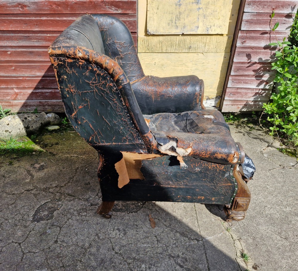 A Victorian library armchair featuring deep buttoned dark leather upholstery with carved wooden arm supports and feet. View III