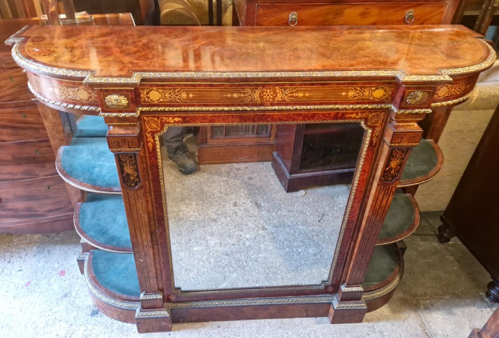 An antique burr walnut side cabinet featuring intricate marquetry inlays, gilt bronze mounts, a central mirror, and open curved side shelves lined in green velvet.