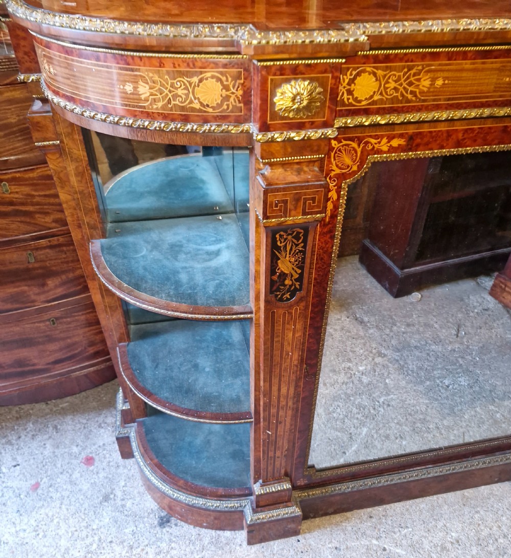 An antique burr walnut side cabinet featuring intricate marquetry inlays, gilt bronze mounts, a central mirror, and open curved side shelves lined in green velvet. View VIII