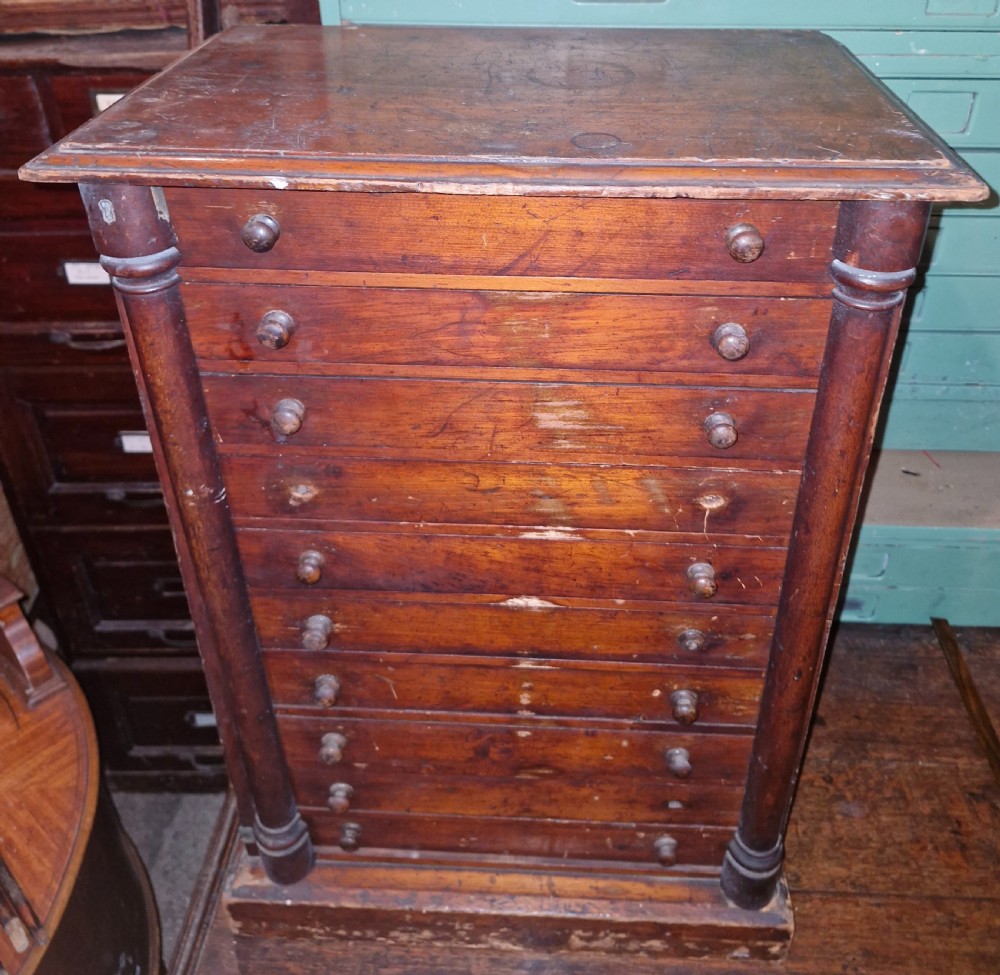 A tall Victorian mahogany specimen cabinet featuring multiple shallow drawers, round turned wood knobs, and side columns.