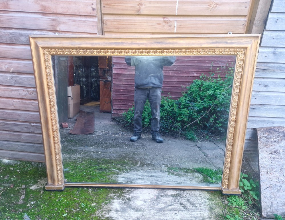 A large 19th-century rectangular overmantel mirror featuring an ornate gilded frame with classical repeating egg-and-dart moulding.