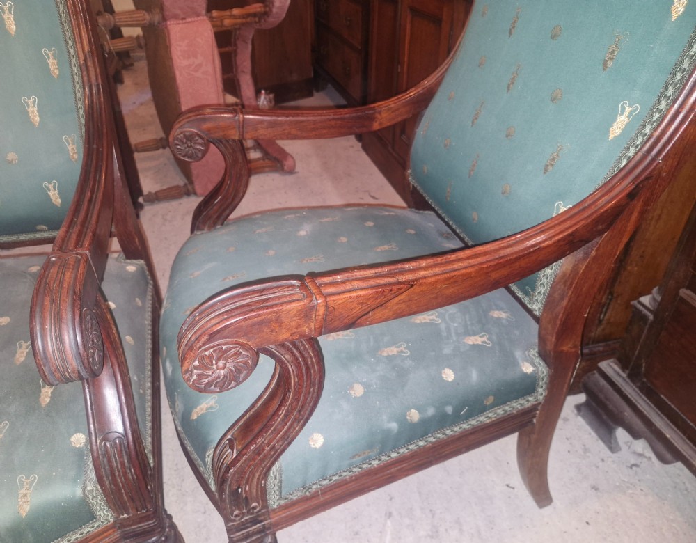 A pair of antique rosewood armchairs featuring carved cresting, curved scroll arms, turned front legs on castors, and green patterned upholstery. View VIII
