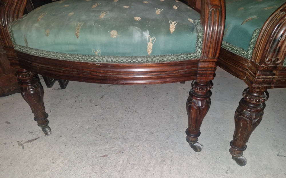 A pair of antique rosewood armchairs featuring carved cresting, curved scroll arms, turned front legs on castors, and green patterned upholstery. View XII