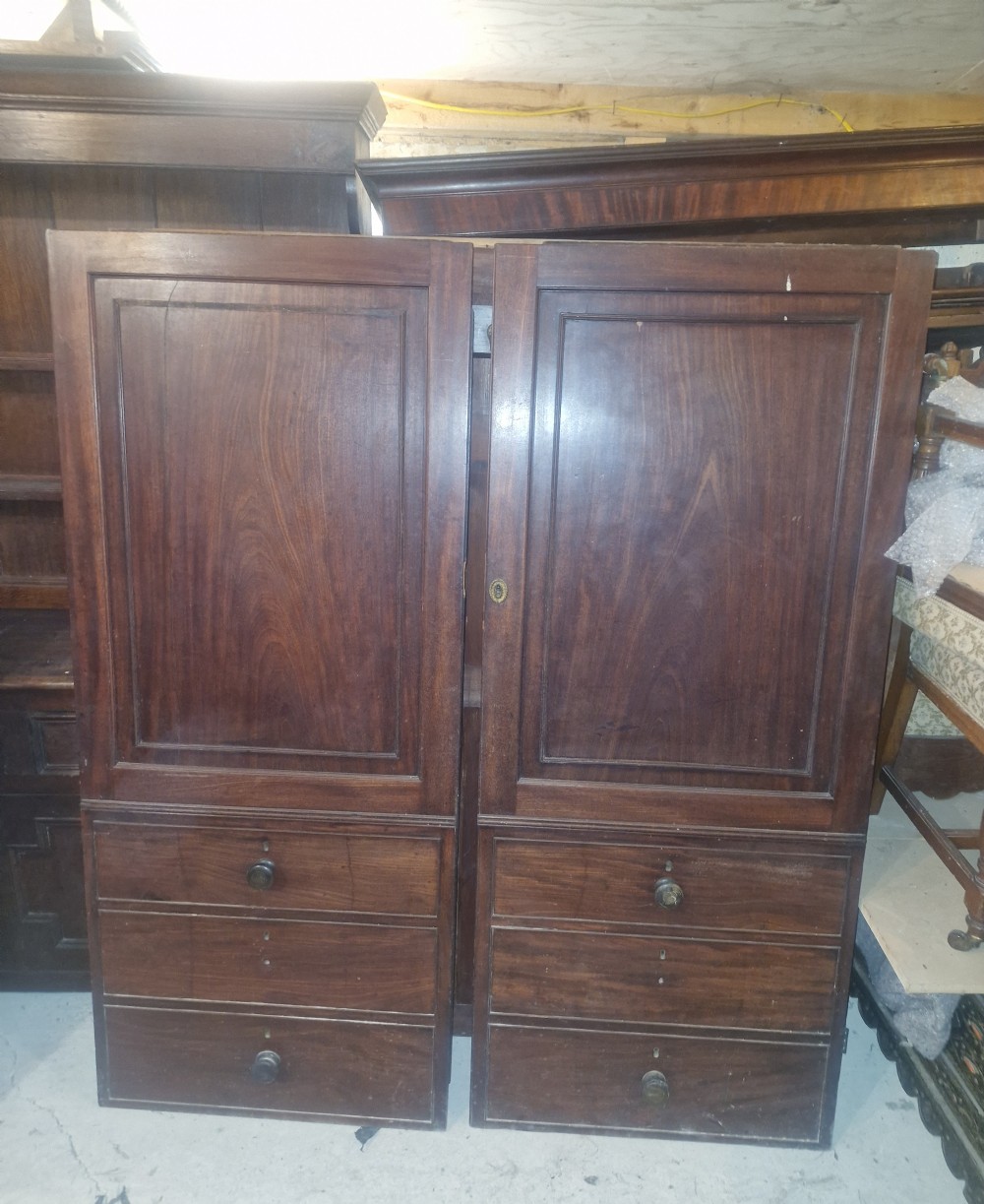 A Late Georgian mahogany wardrobe featuring two large panelled doors above multiple lower drawers with turned wooden knobs.