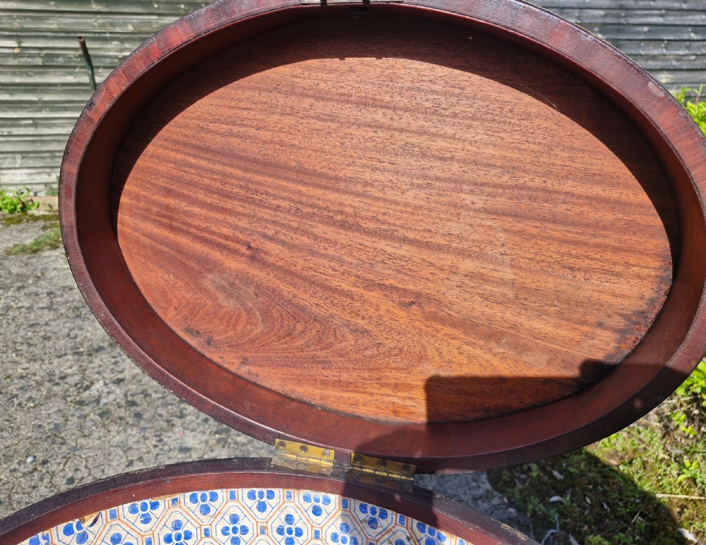 An early nineteenth-century oval mahogany wine cellarette featuring brass binding, lion mask side handles, and tapered legs on brass castors. View VII
