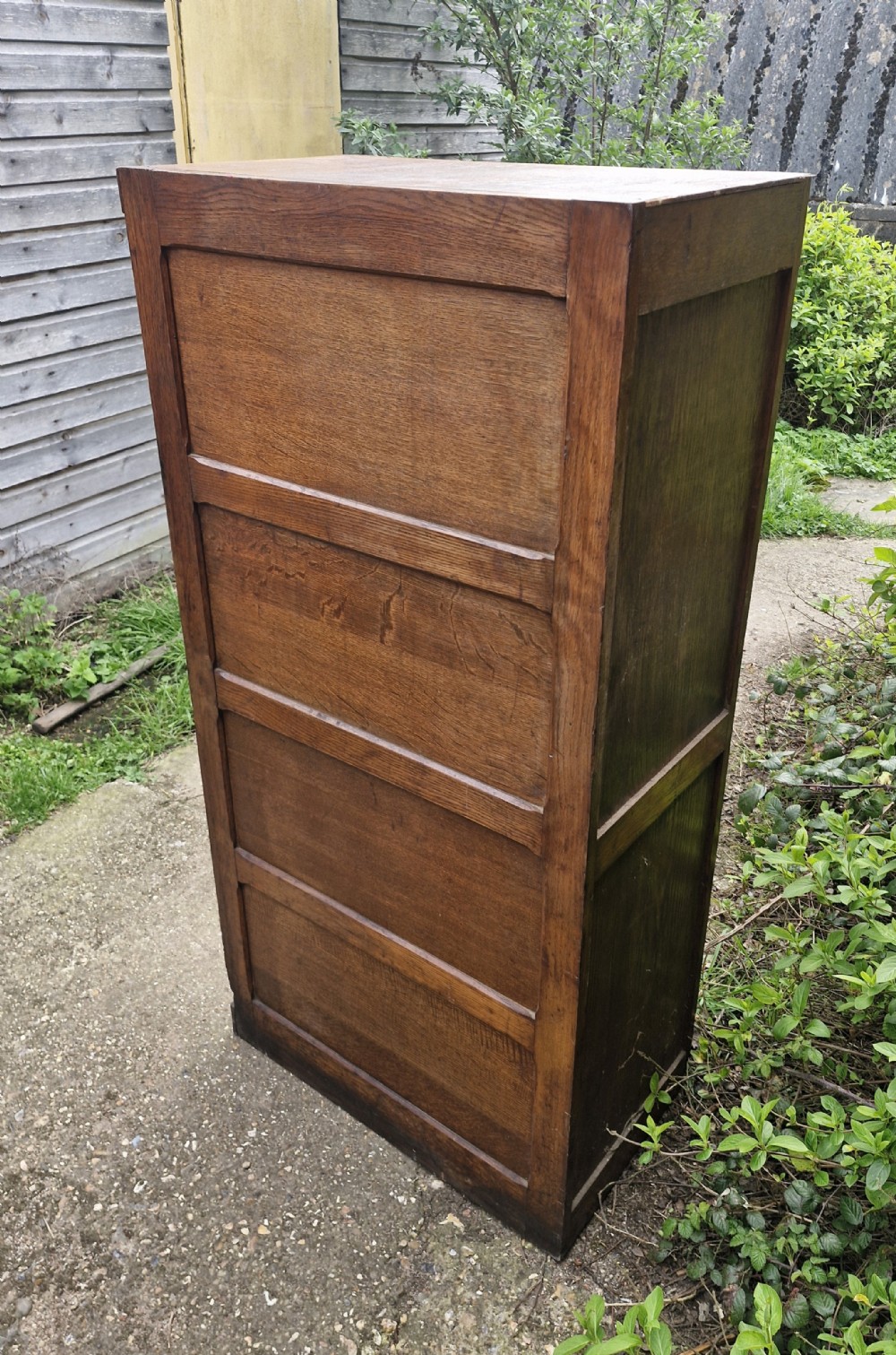 A tall oak four-drawer vertical filing cabinet featuring panelled sides and brass cup handles. View VI