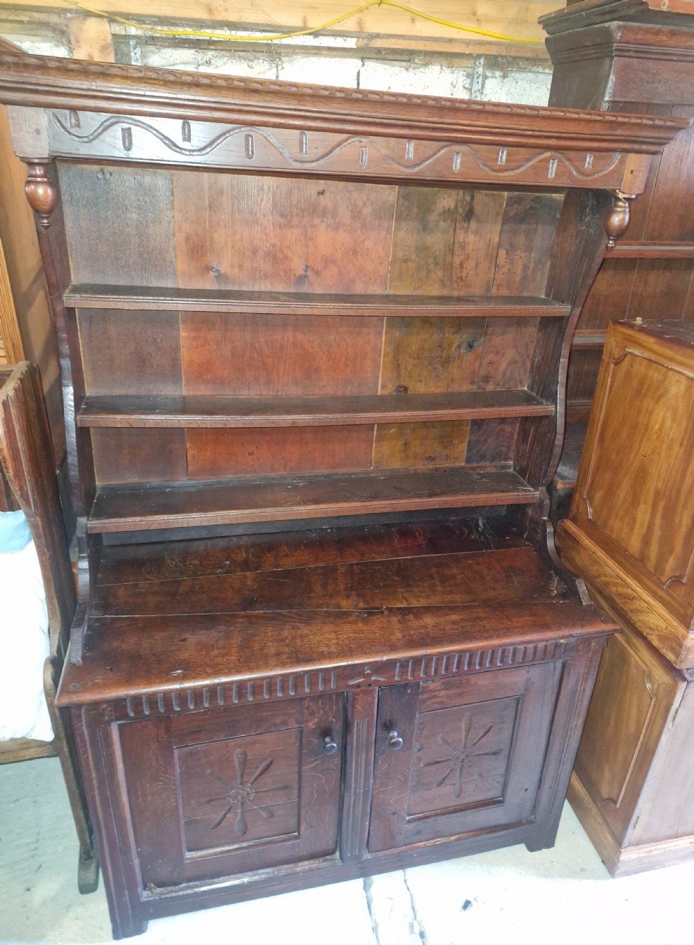 A dark oak cottage dresser featuring a three-tier open plate rack mounted above a two-door base cabinet with carved panel motifs. View II