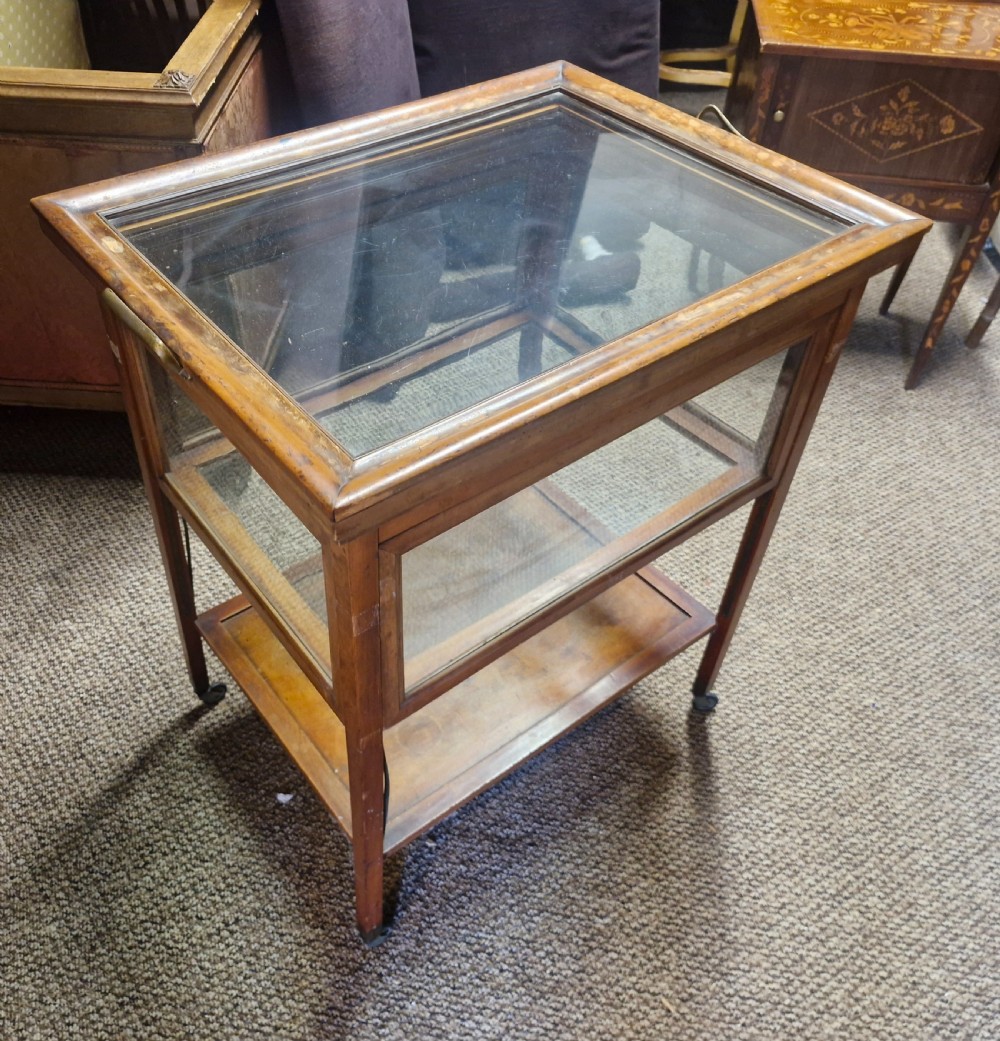 A glazed wooden tea trolley featuring glass side panels, a glass top surface, brass handles, a lower shelf, and castors. View VI