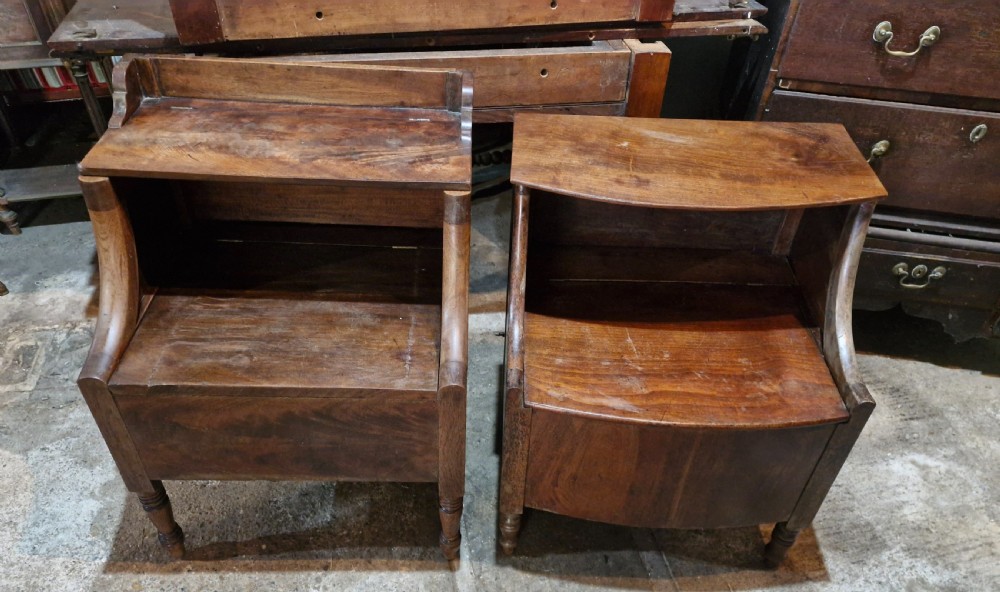 A pair of late Georgian mahogany two-tiered bedside tables with turned front legs and curved side supports.