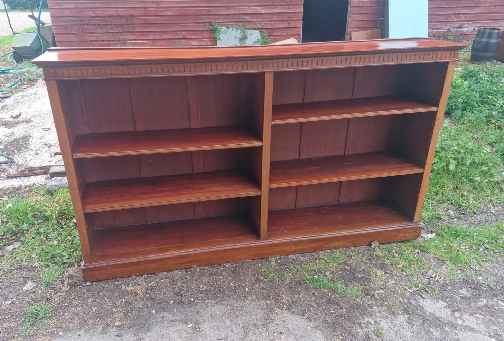 A wide Edwardian mahogany low open-front bookcase with two central bays, adjustable internal shelves, and dentil moulding along the top edge.