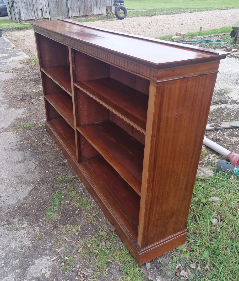 A wide Edwardian mahogany low open-front bookcase with two central bays, adjustable internal shelves, and dentil moulding along the top edge. View IV