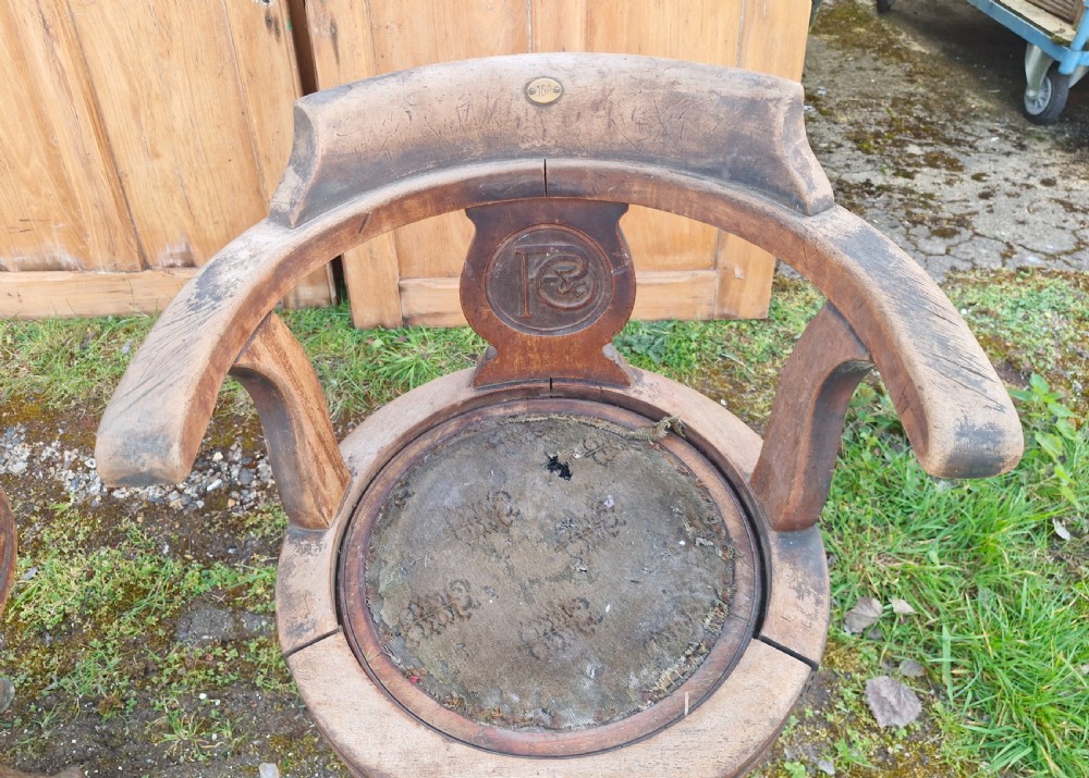 A pair of antique wooden ocean liner revolving armchairs featuring carved monograms on the back splats and cast iron swivel bases. View IV