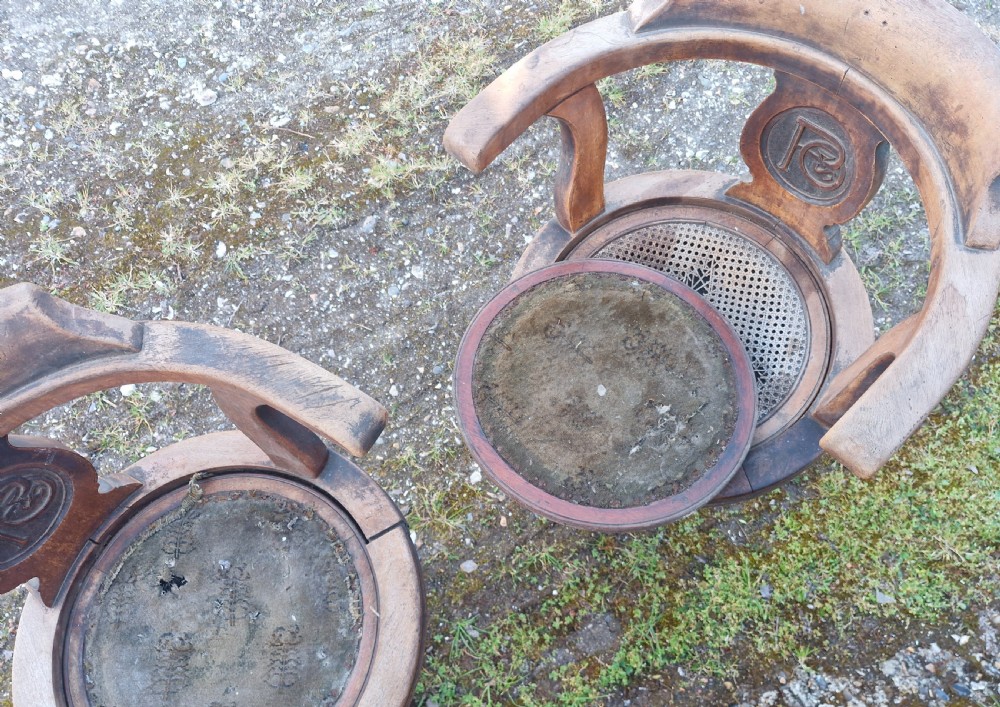 A pair of antique wooden ocean liner revolving armchairs featuring carved monograms on the back splats and cast iron swivel bases. View V