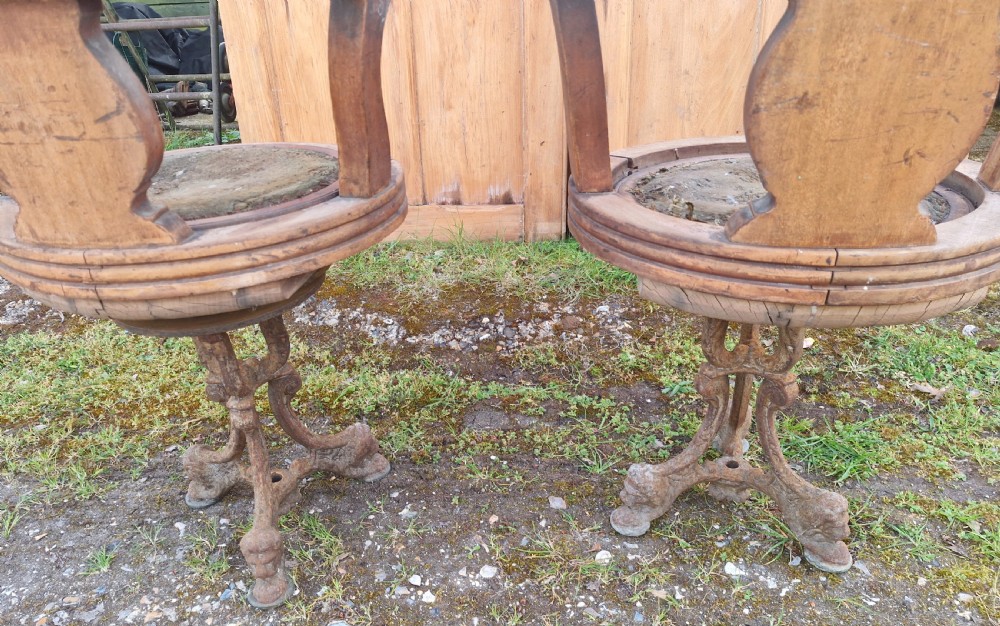 A pair of antique wooden ocean liner revolving armchairs featuring carved monograms on the back splats and cast iron swivel bases. View VI