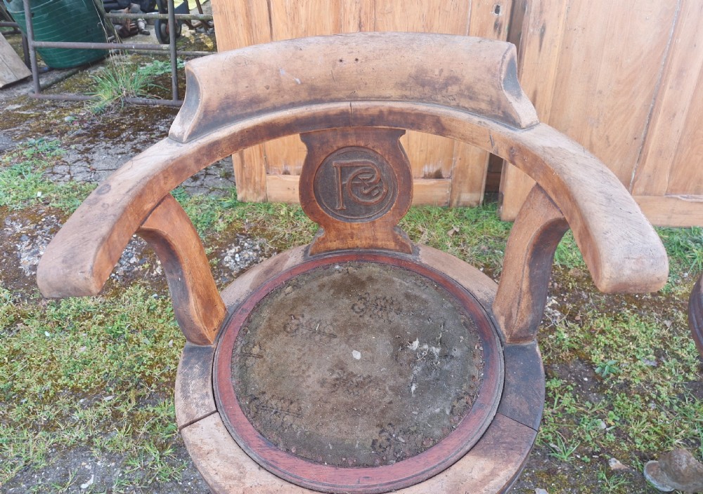 A pair of antique wooden ocean liner revolving armchairs featuring carved monograms on the back splats and cast iron swivel bases. View VIII