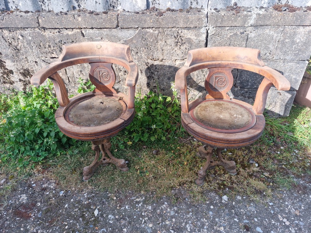 A pair of antique wooden ocean liner revolving armchairs featuring carved monograms on the back splats and cast iron swivel bases. View XI