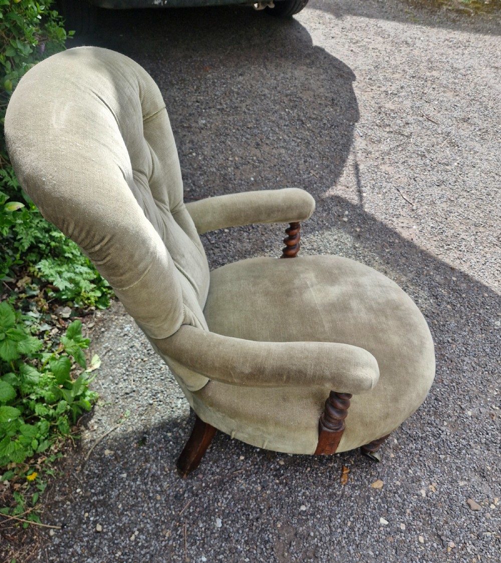 A mid-Victorian armchair upholstered in sage green velvet featuring a deep buttoned backrest, padded arms on barley twist supports, and turned legs with castors. View II